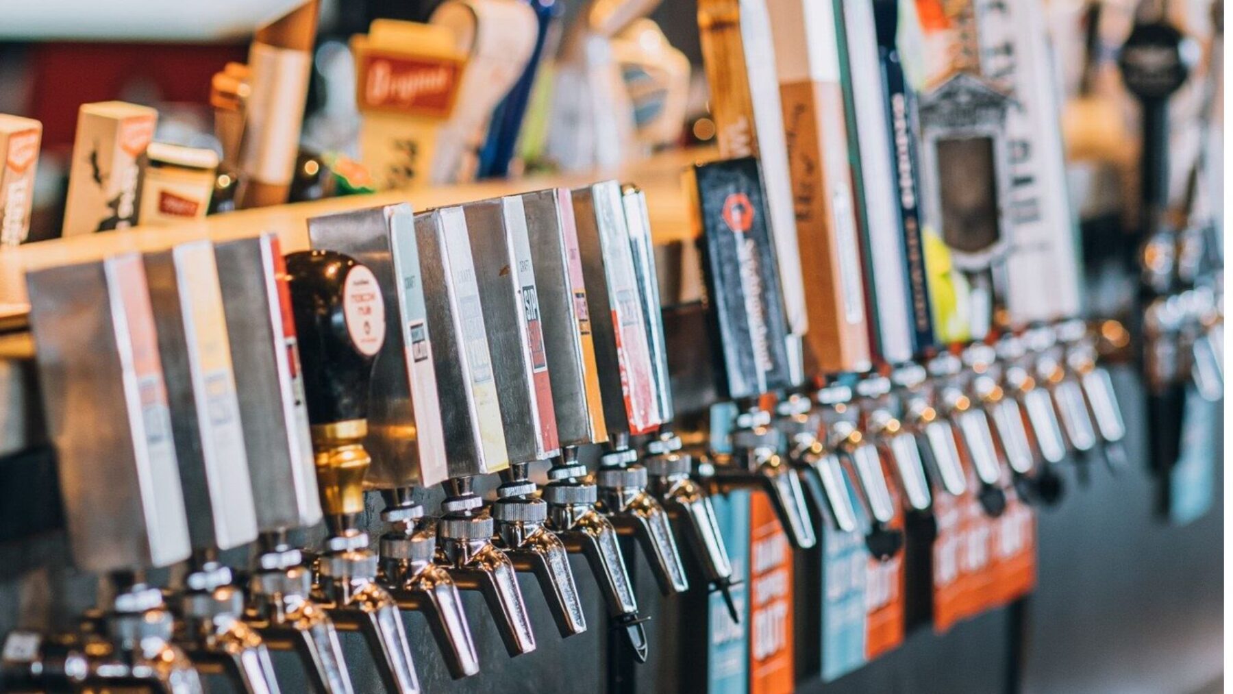 CRAFT Beer Market A row of beer taps lined up at a bar, each with a different branded handle, ready for serving draft drinks—perfect for group bookings or trying craft cocktails across multiple locations.