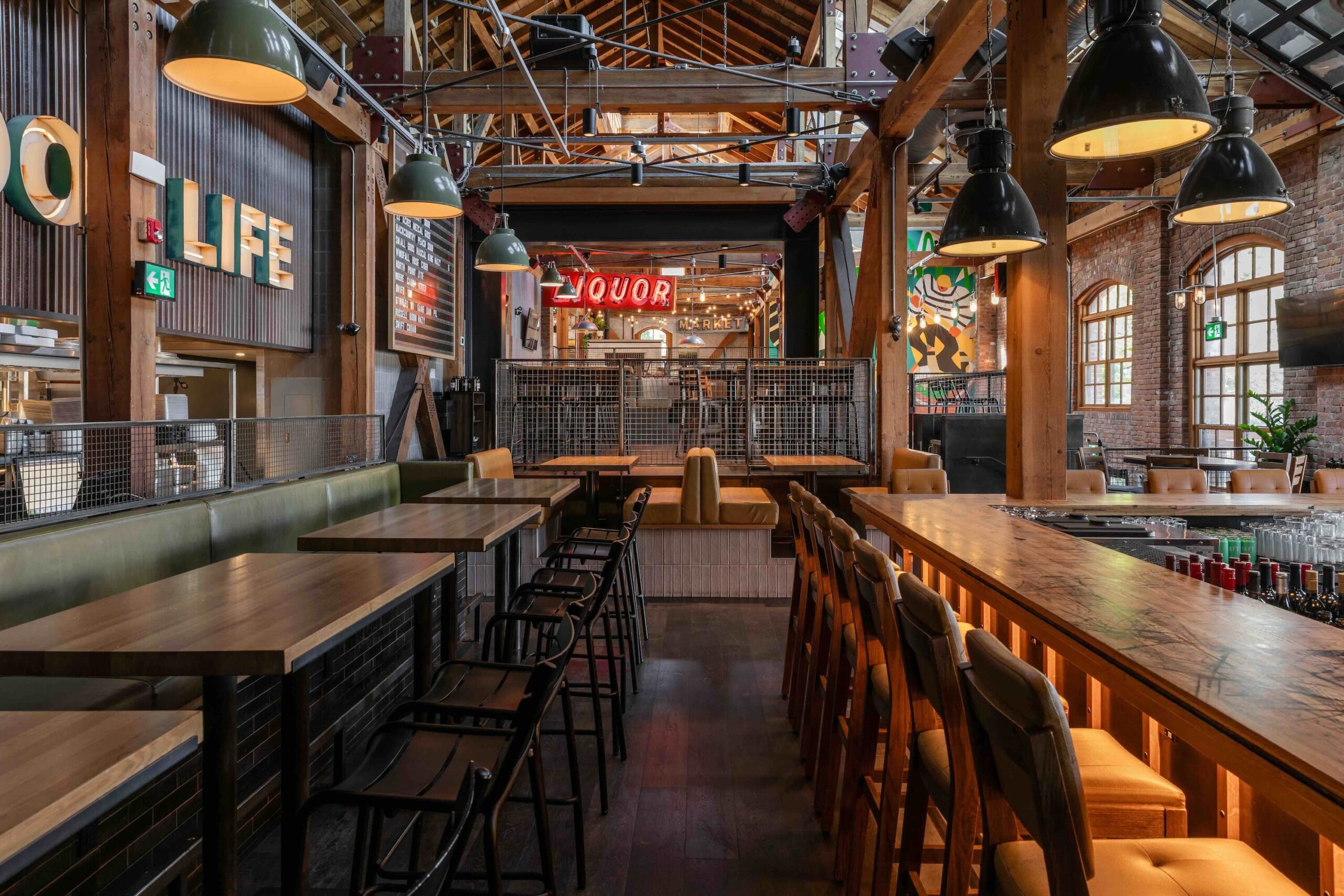 CRAFT Beer Market Spacious industrial-style bar and restaurant with wooden beams, high ceilings, large windows, neon signs reading "LIFE" and "LIQUOR," plus a vibrant beer garden and a menu of inventive craft cocktails.